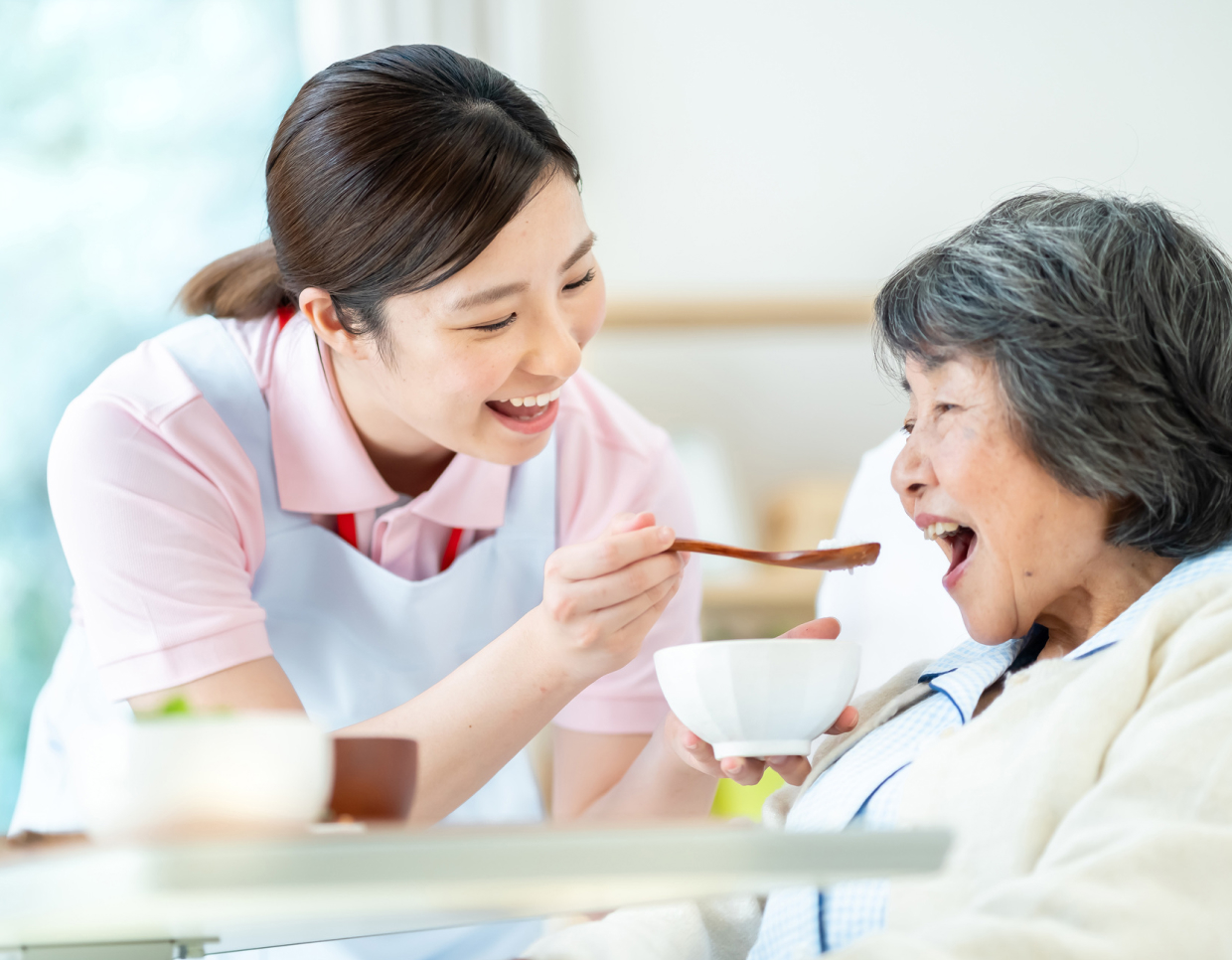食事の介助をしている介護士とおばあちゃん